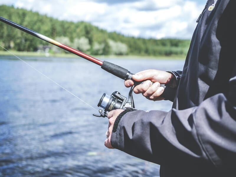 Gros plan sur les mains d'une personne tenant une canne à pêche lors d'un stage de pêche près d'Agen.