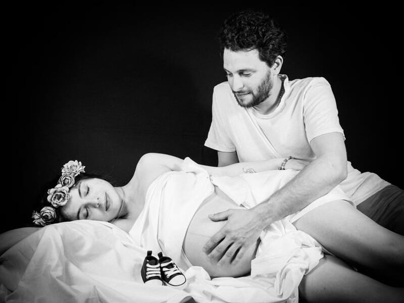 Photo en noir et blanc d'un couple avec femme enceinte, homme touchant son ventre,lors d'un shooting avec un photographe de grossesse à Nîmes.