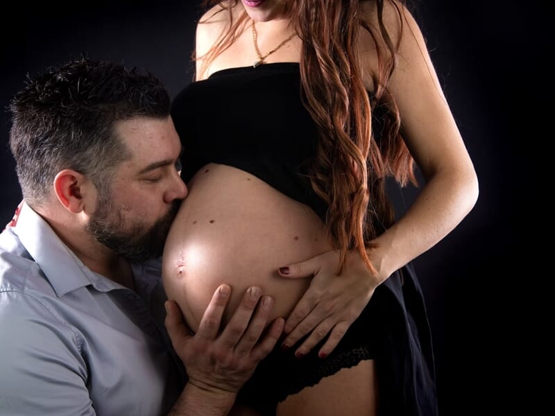 Homme embrassant le ventre nu de sa compagne enceinte, lors d'un shooting avec un photographe de grossesse à Nîmes.