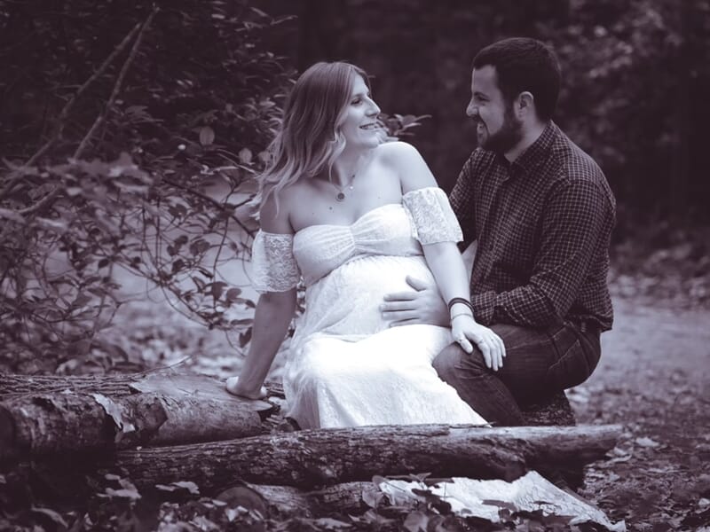 Un couple assis sur des troncs d'arbre en forêt,lors d'un shooting photo couple à Nîmes.