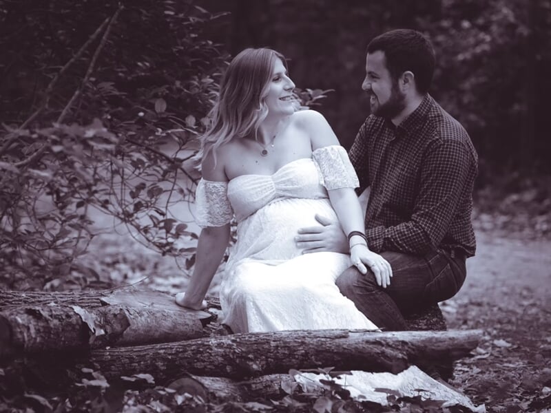 Un couple assis sur des troncs d'arbre en forêt,lors d'un shooting photo couple à Nîmes.