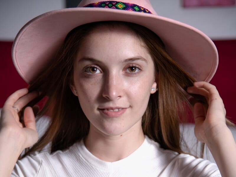 Portrait d'une jeune femme souriante portant un chapeau rose lors d'un shooting photo portrait à Nîmes.