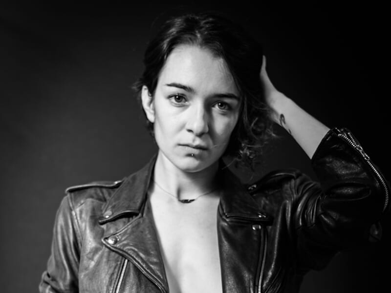 Portrait en noir et blanc d'une femme au regard intense, vêtue d'une veste en cuir lors d'un shooting photo portrait à Nîmes.
