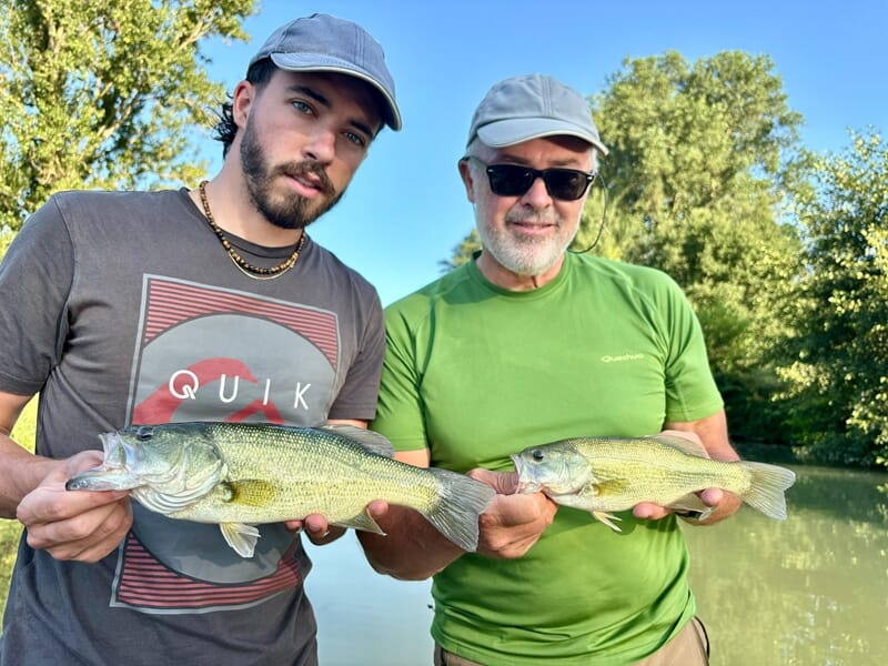 Deux hommes souriants montrent chacun un poisson qu'ils ont pêché lors d'un stage de pêche près d'Agen.