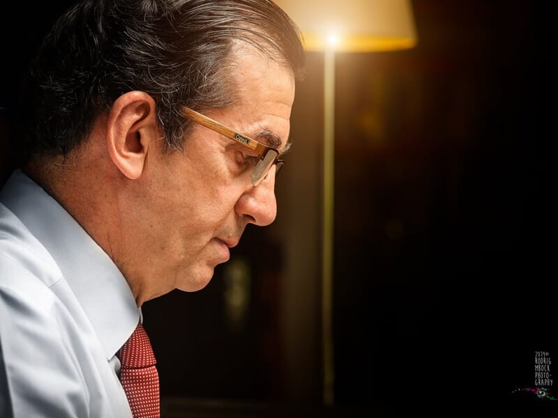 Homme mûr en chemise blanche et cravate rouge, regard concentré lors d'un shooting photo lifestyle au Mans.