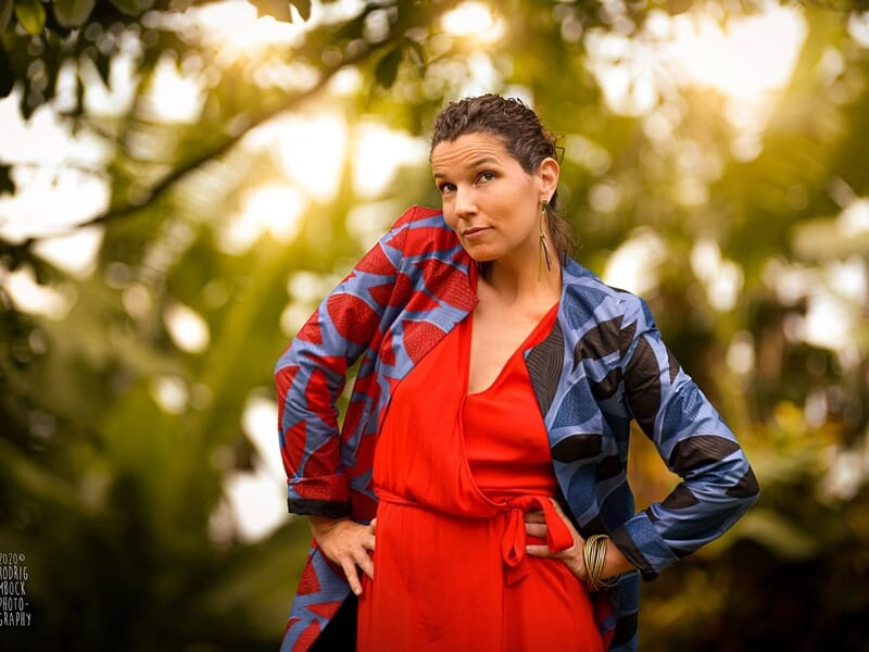Femme en robe rouge et veste colorée, posant avec confiance lors d'un shooting photo lifestyle au Mans.