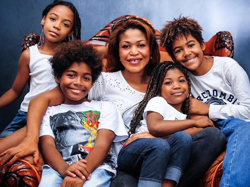 Portrait chaleureux d'une femme souriante entourée de quatre enfants lors d'un shooting photo famille au Mans.