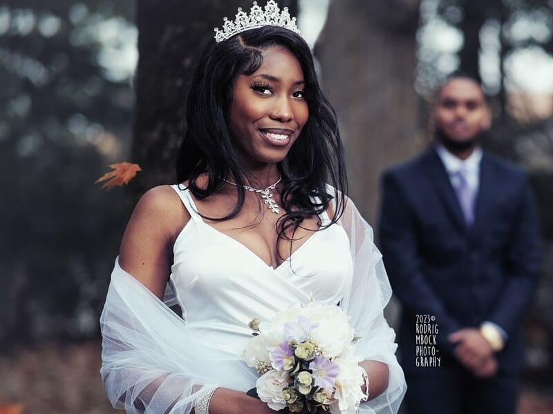 Jeune mariée souriante portant une robe blanche et une couronne lors d'un shooting photo grossesse au Mans.
