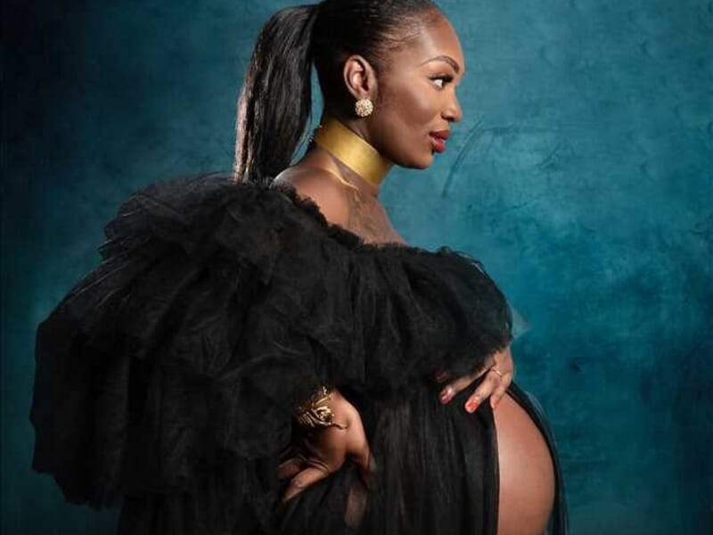 Portrait d'une femme enceinte en robe noire transparente avec un collier doré lors d'un shooting photo grossesse au Mans.