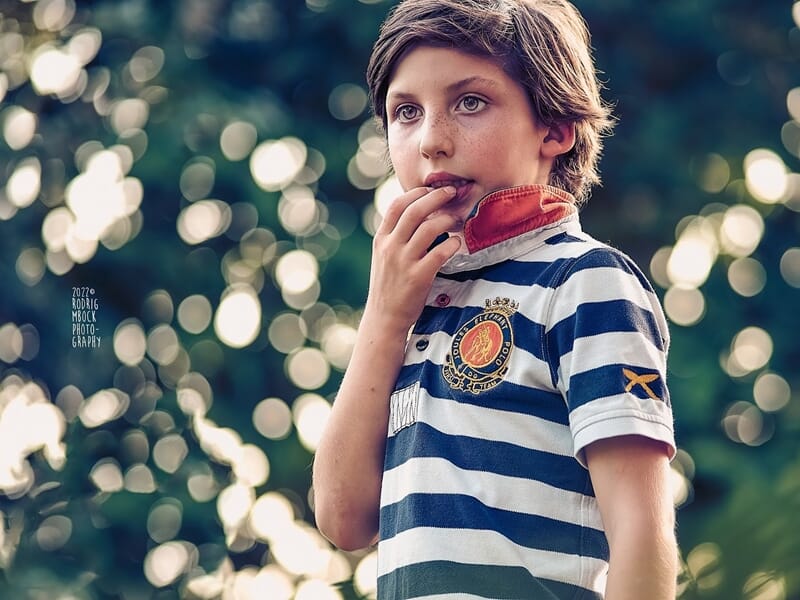 Garçon aux cheveux clairs portant un polo rayé bleu et blanc, pensif, lors d'un shooting photo portrait au Mans.