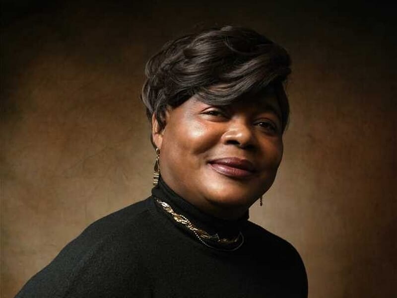 Portrait d'une femme souriante avec un pull noir et un collier lors d'un shooting photo portrait au Mans.