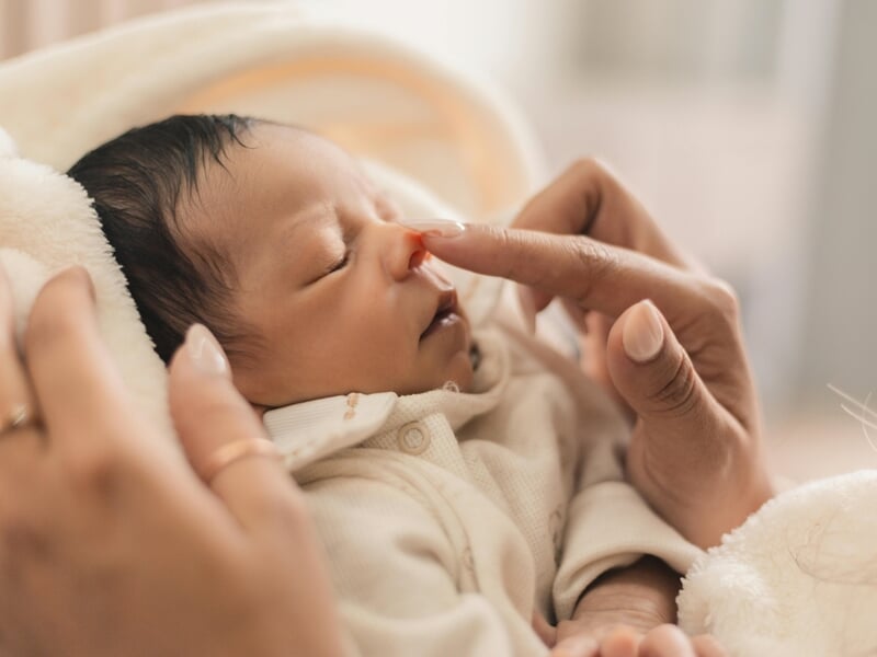Un nouveau-né endormi, enveloppé dans une couverture lors d'un shooting photo bébé au Mans.
