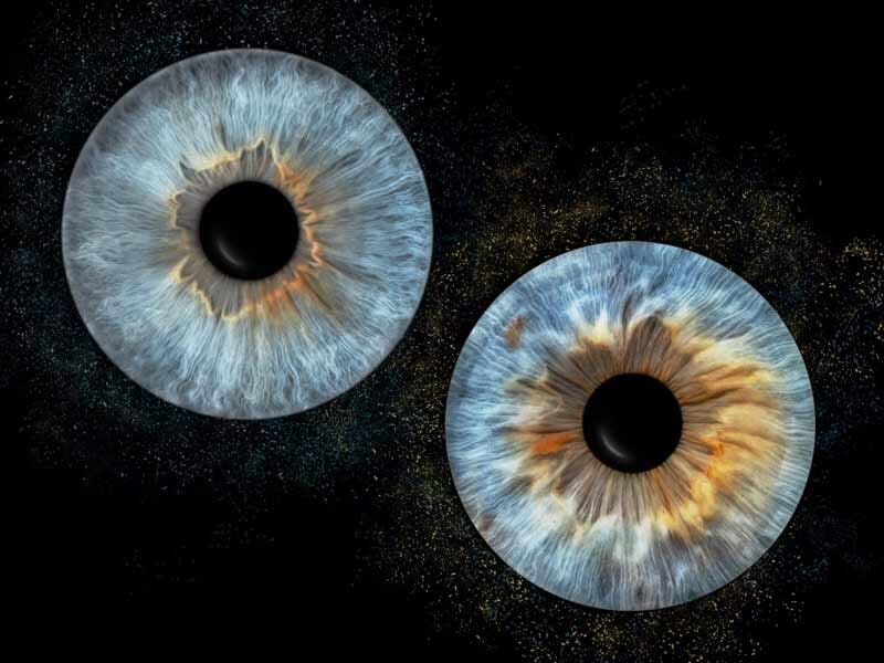 Deux iris humains détaillés en gros plan, aux couleurs bleues et brunes, sur fond noir étoilé