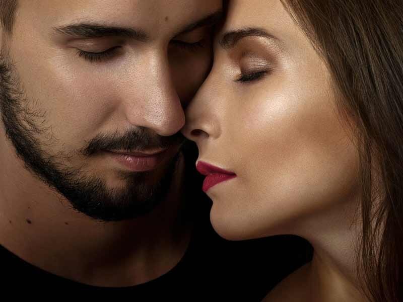 Portrait rapproché d'un couple avec les yeux fermés, partageant un moment intime et tendre.