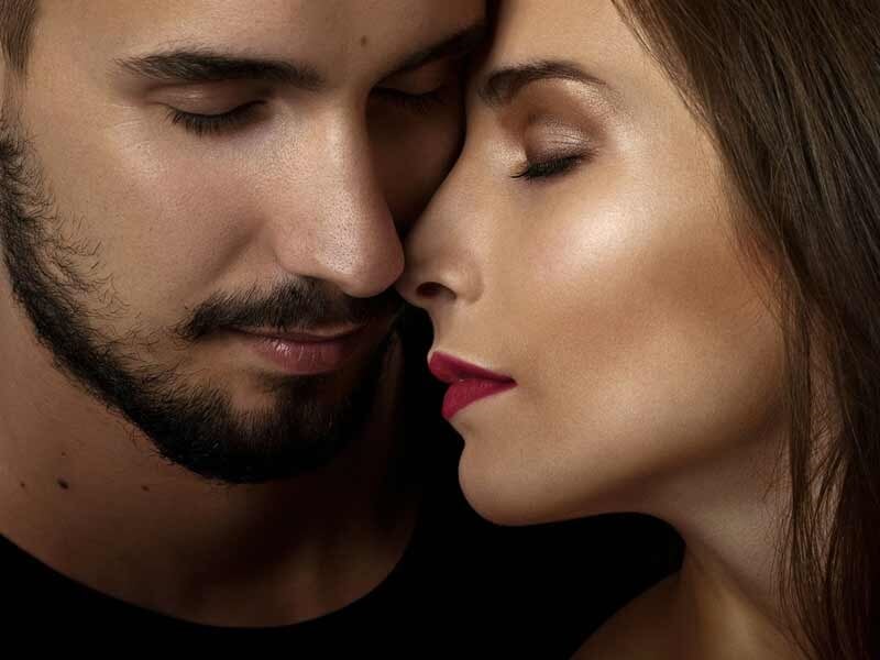 Portrait rapproché d'un couple avec les yeux fermés, partageant un moment intime et tendre.