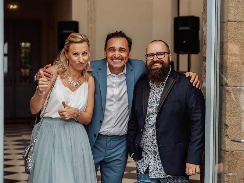 Trois adultes souriants posant ensemble dans un cadre intérieur élégant, ambiance conviviale et chaleureuse.