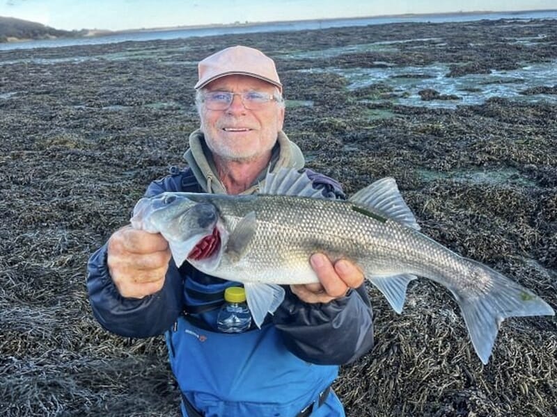 Homme âgé en tenue de pêche tenant un gros poisson lors d'un stage de pêche à Saint-Pol-de-Léon.