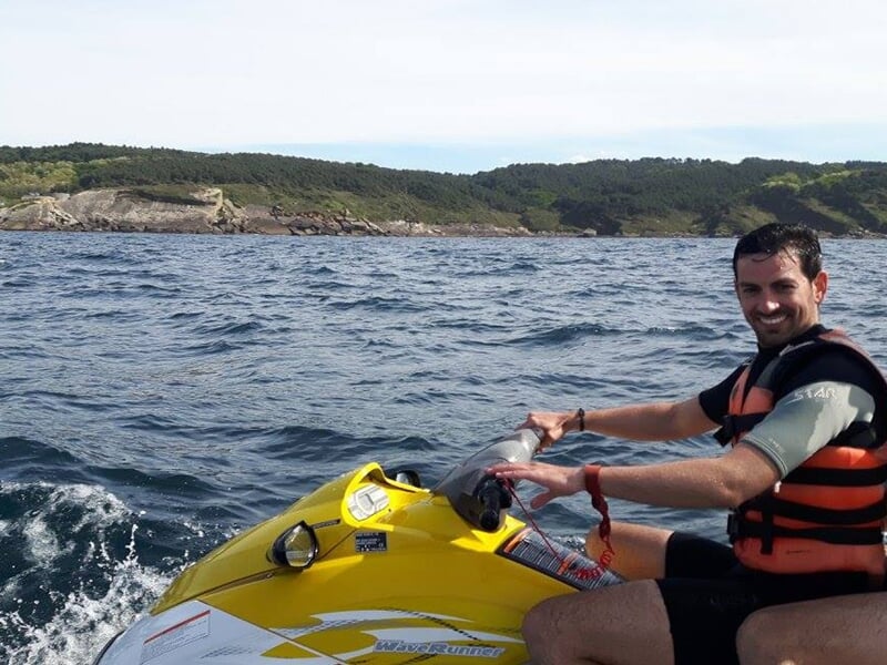 Jet ski rouge sur un plan d'eau avec un ciel bleu et des collines en arrière-plan