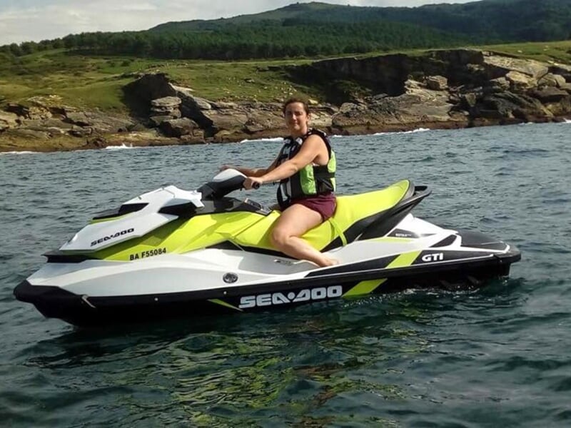 Jet ski rouge sur un plan d'eau avec un ciel bleu et des collines en arrière-plan