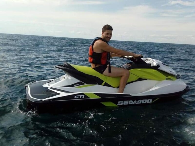 Personne en jet ski sur un lac avec un ciel clair et des collines en arrière-plan