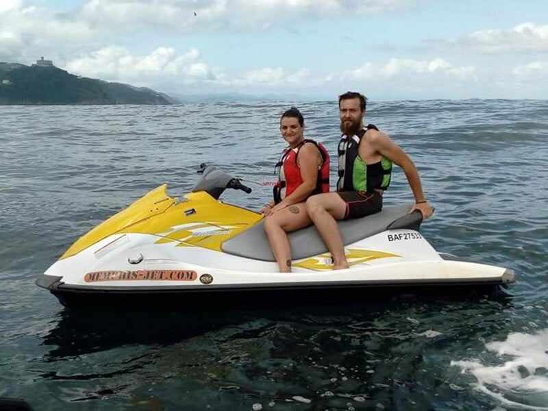 Jet ski rouge sur un plan d'eau avec un ciel bleu et des collines en arrière-plan