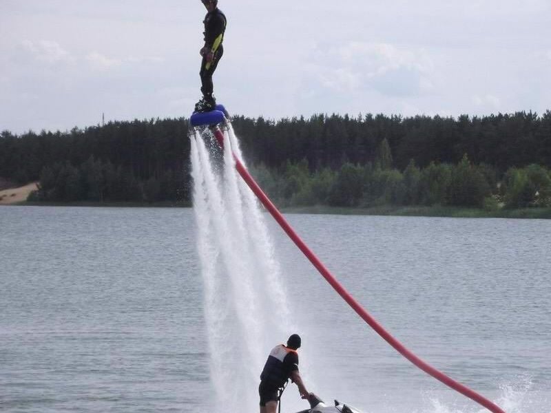 Personne en flyboard réalisant une figure avec un jet d'eau puissant sur un lac