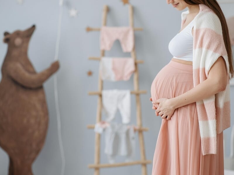 Femme enceinte en robe longue rose et gilet rayé lors d'un shooting photo grossesse à Caen