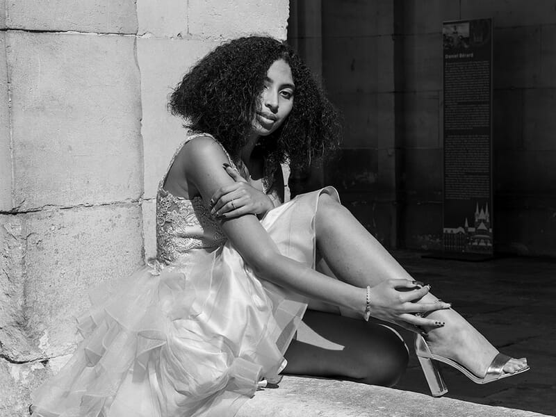Portrait en noir et blanc d'une femme assise, en robe claire, lors d'un shooting photo portrait à Caen.