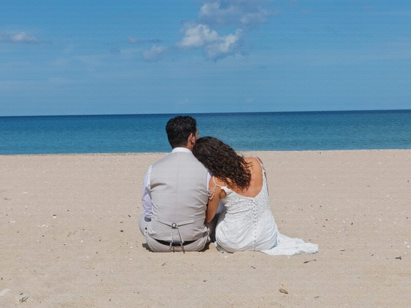 Un couple assis sur une plage de sable face à la mer lors d'un shooting photo à Caen.