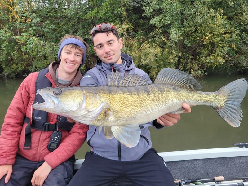 Deux jeunes hommes souriants lors d'un stage de pêche en bateau sur la Seine à Poissy.