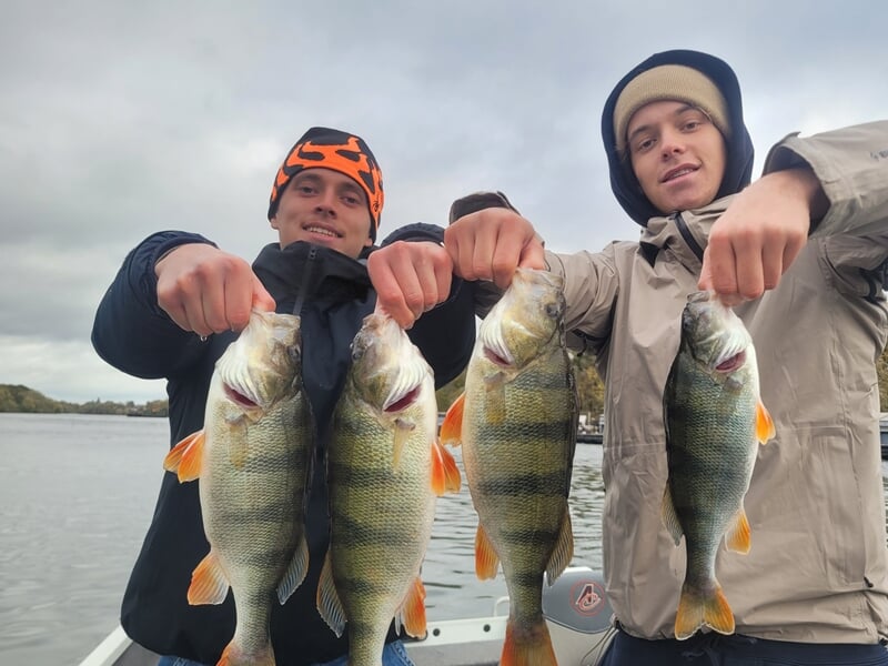 Deux hommes montrant chacun deux poissons lors d'un stage de pêche en bateau sur la Seine à Poissy.