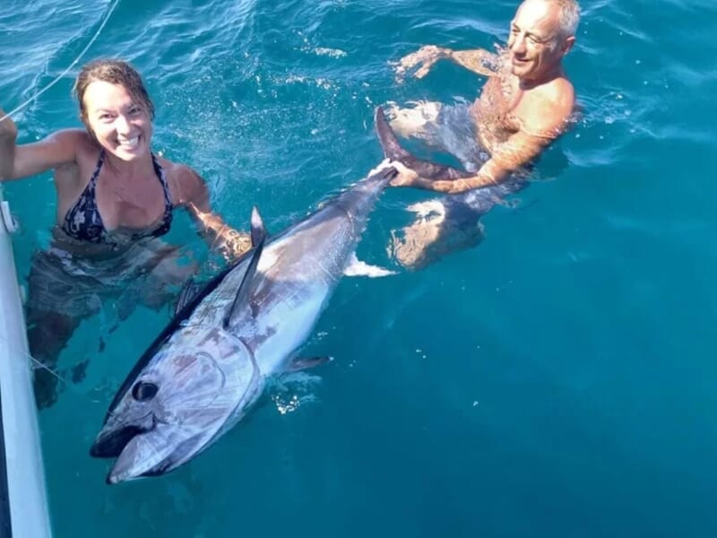 Un homme et une femme dans l'eau tenant un gros poisson entre eux lors d'une sortie pêche à Saintes-Maries-de-la-Mer.