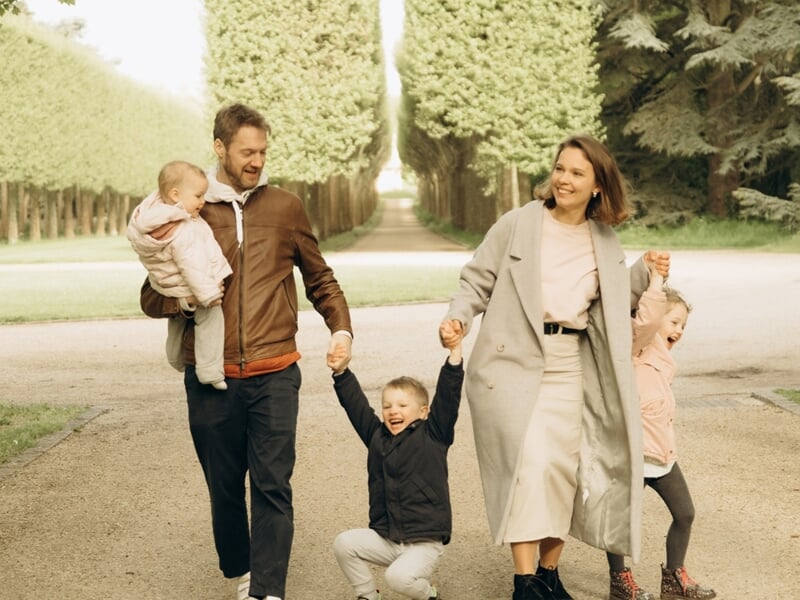 Une famille heureuse avec deux enfants marche main dans la main lors d'un shooting photo famille à Maisons-Laffitte.
