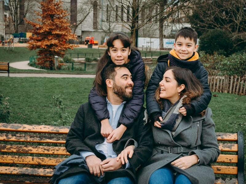 Un couple souriant avec deux enfants assis sur un banc lors d'un shooting photo famille à Maisons-Laffitte.