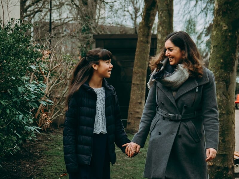 Une femme et une jeune fille marchent main dans la main lors d'un shooting photo famille à Maisons-Laffitte.