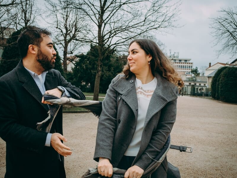 Un homme et une femme discutent dans un parc en hiver, vêtus de manteaux lors d'un shooting photo couple à Maisons-Laffitte.