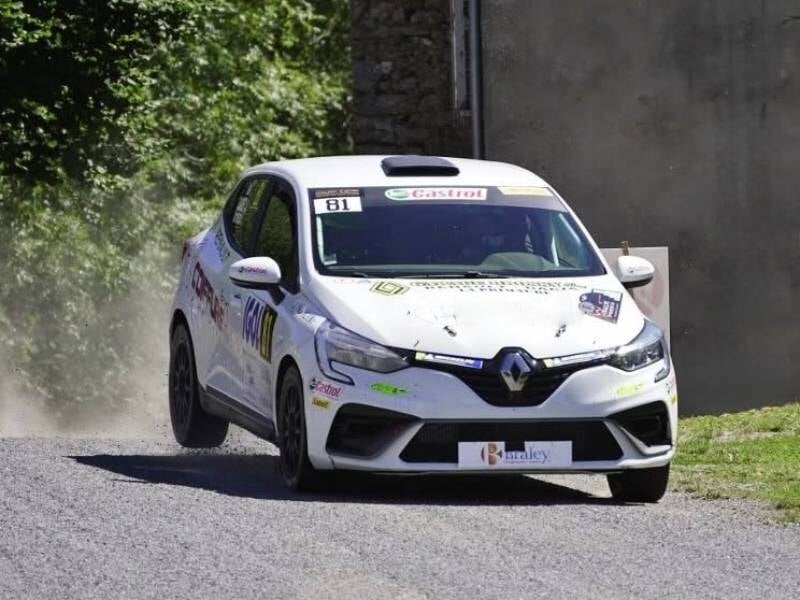 Voiture de course blanche sur une route d'asphalte, en pleine accélération avec poussière soulevée en arrière, lors d'un stage de pilotage rallye au circuit du Roussillon.