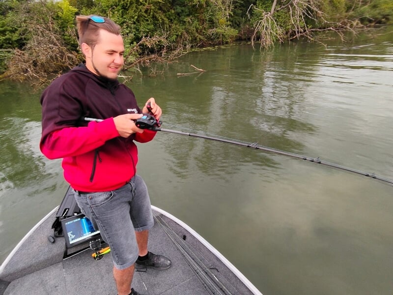 Jeune homme en veste rouge et noire tenant une canne à pêche lors d'un stage de pêche près de Dijon.