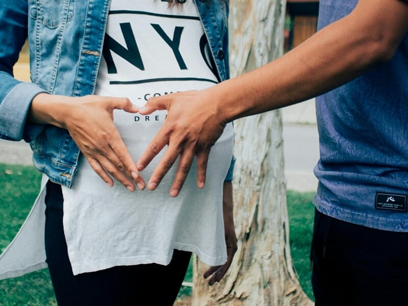 Couple formant un cœur avec leurs mains sur le ventre de la femme enceinte lors d'un shooting photo grossesse à Dunkerque.