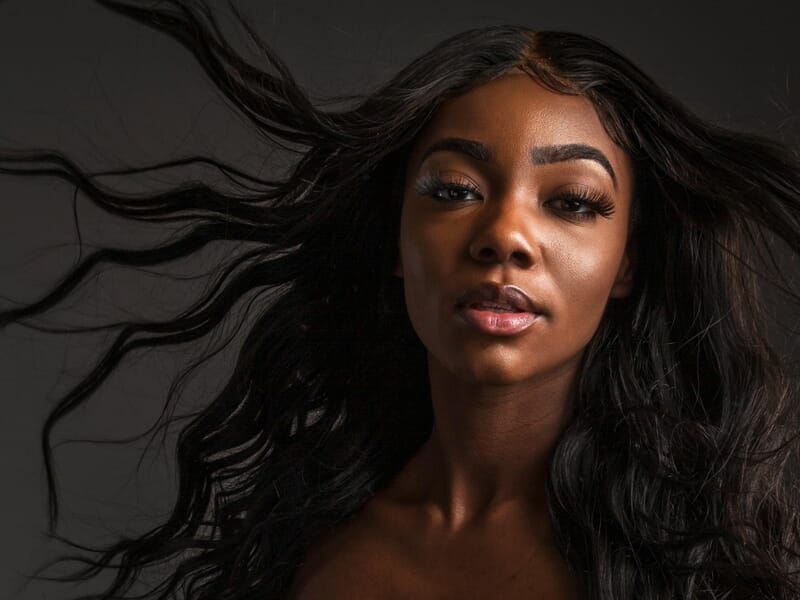 Portrait d'une femme noire aux longs cheveux noirs flottants, lors d'un shooting photo portrait à Dunkerque.