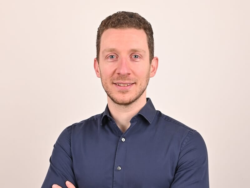 Portrait d'un homme souriant aux cheveux courts, portant une chemise bleue lors d'un shooting photo portrait à Dunkerque.