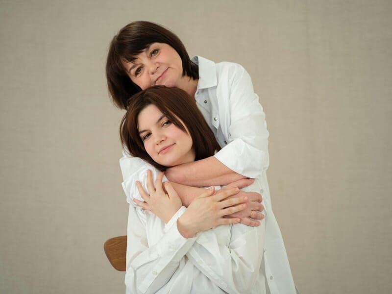 Une femme aux cheveux courts embrasse tendrement une jeune femme brune, lors d'un shooting photo de famille près de Nancy.