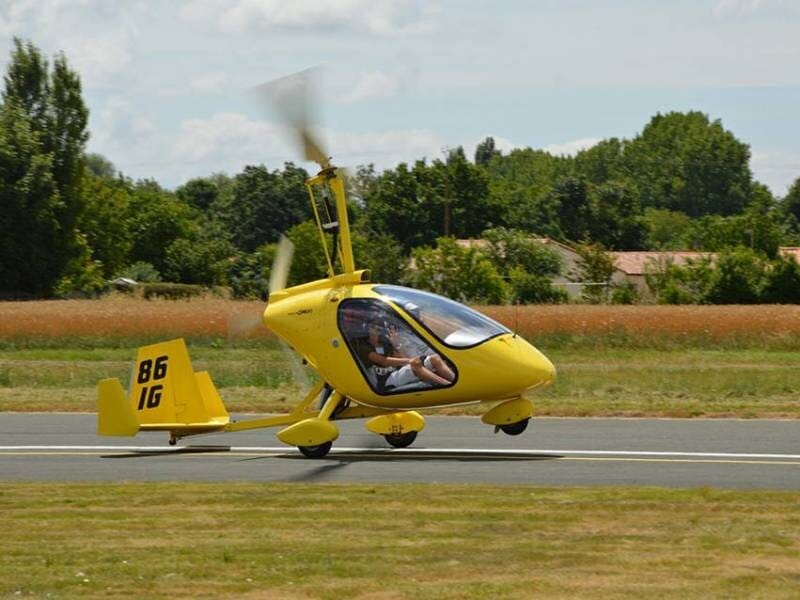 ULM jaune décollant sur une piste avec un pilote visible à bord, lors d'une initation au pilotage d'ULM, dans le Marais poitevin.