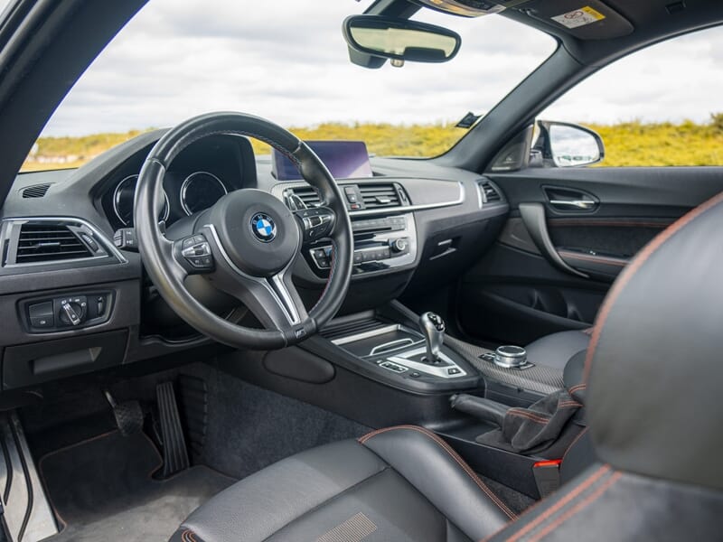 Intérieur d'une voiture BMW avec volant, tableau de bord et sièges en cuir noir lors d'un stage de pilotage glisse sur circuit.