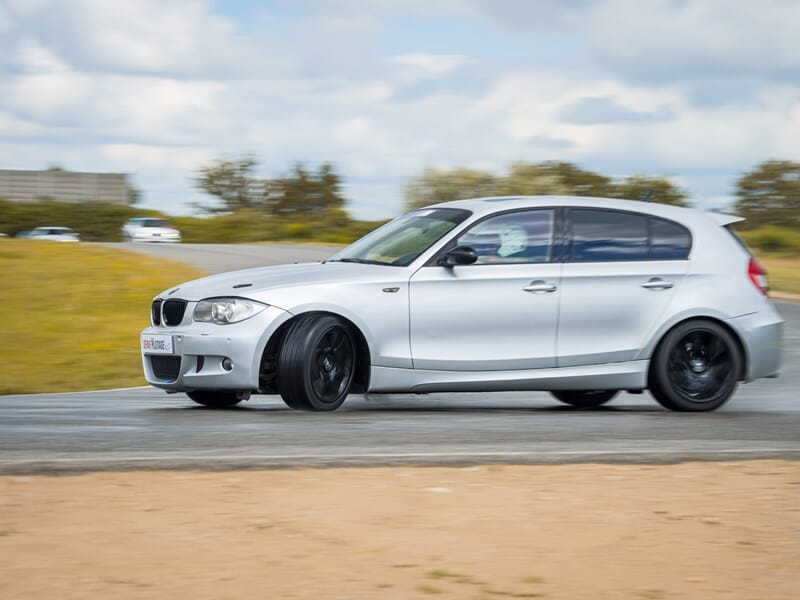 Voiture BMW blanche roulant sur circuit, floue en mouvement lors d'un stage de pilotage glisse sur circuit.