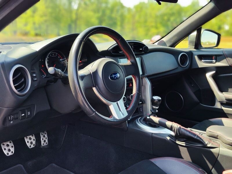 Intérieur d'une voiture sportive avec volant, tableau de bord et pédales en aluminium, ambiance sportive.