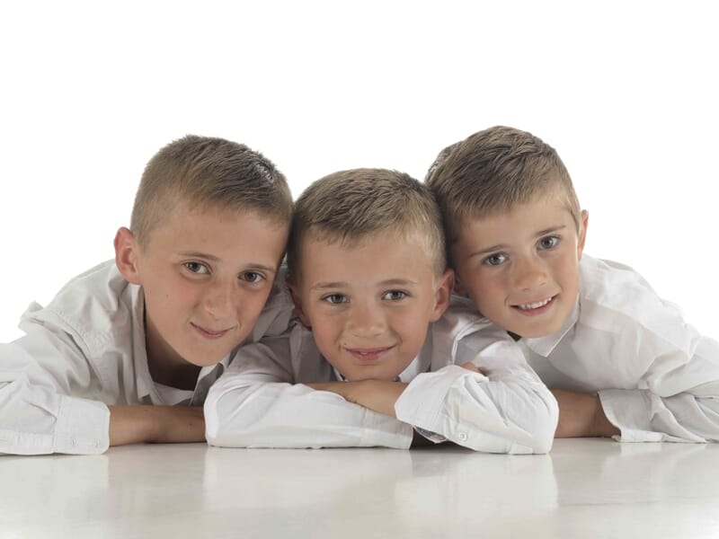 Trois garçons souriants en chemises blanches posent allongés lors d'un shooting photo famille à Colmar.