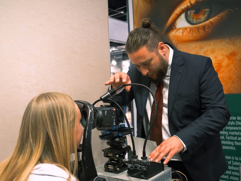 Un homme en costume ajuste une caméra professionnelle pendant qu'une femme blonde regarde à travers l'objectif lors d'un shooting photo.
