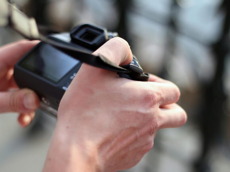 Main tenant un appareil photo compact noir, lors d'un stage photo à Besançon.