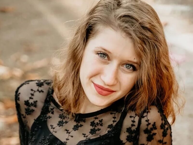 Portrait d'une jeune femme aux cheveux roux et bouclés, portant un haut noir transparent lors d'un shooting lifestyle à Besançon.